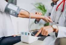 دكتور في عيادة الطب العام يقيس ضغط مريض